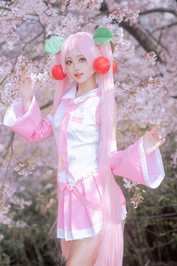 a woman with long pink hair standing in front of cherry blossom trees wearing a costume