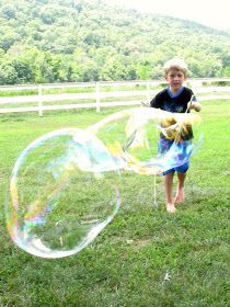 a young boy is playing with bubbles in the grass