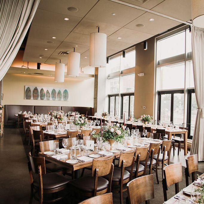 a dining room filled with lots of tables covered in white tablecloths and place settings