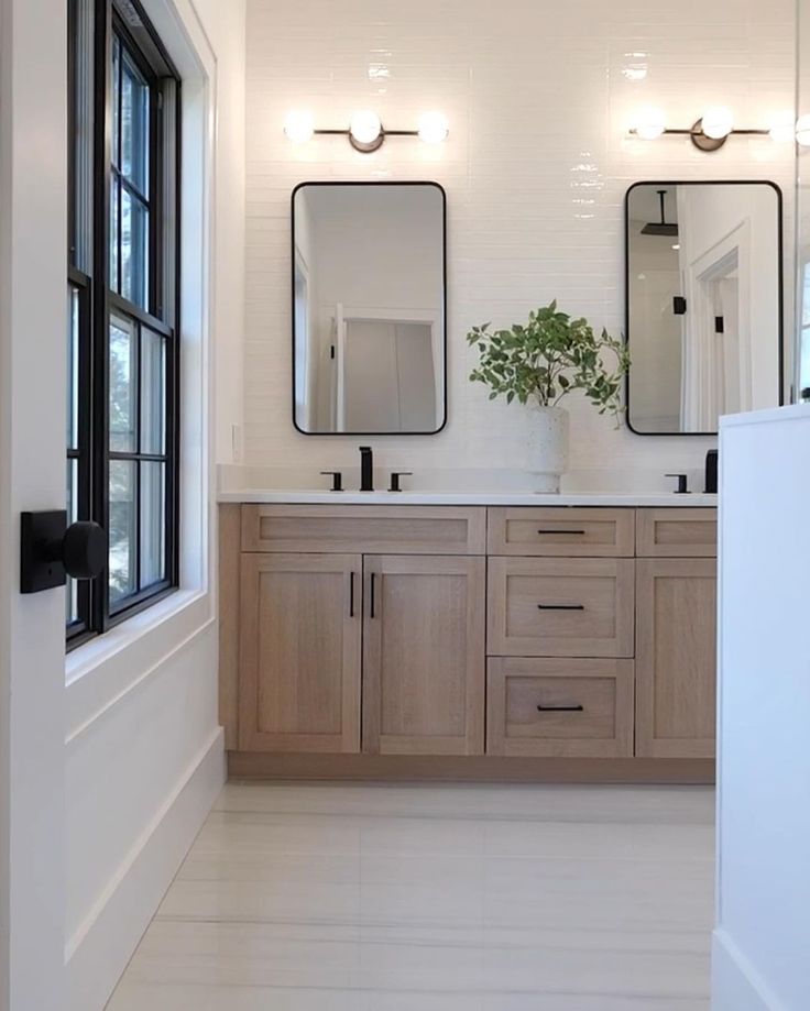 a bathroom with double sinks and two mirrors on the wall next to eachother