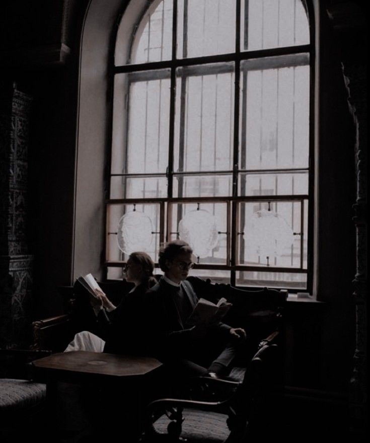 two people sitting on a bench in front of a window