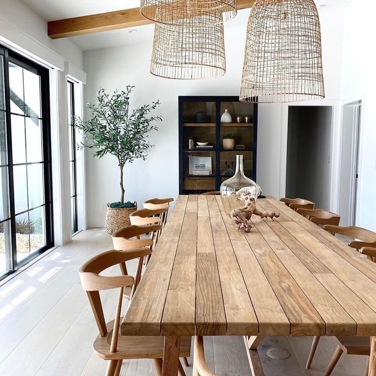 a large wooden table with chairs around it in a room that has glass doors and windows