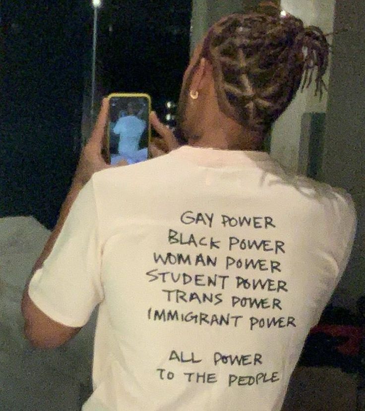 a woman taking a selfie in front of a mirror wearing a t - shirt that reads gay power, black power, women power, student power, and immigrant power