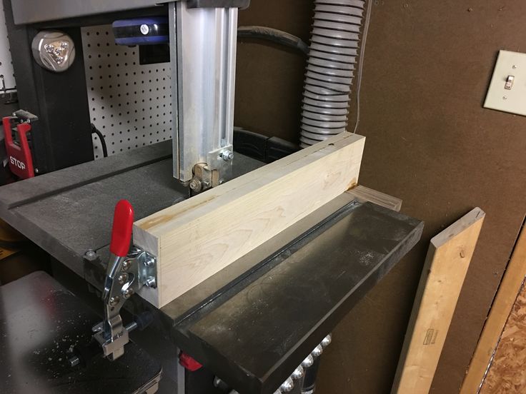 a machine that is working on some kind of piece of wood in a room with other tools