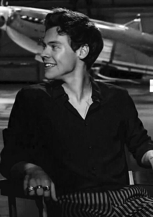 black and white photograph of a man sitting in a chair with an airplane behind him