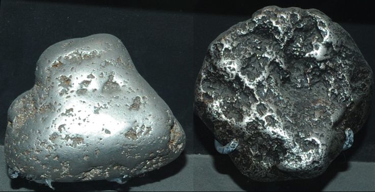 two large rocks sitting next to each other on top of a black surface with silver flecks