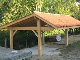 a wooden shelter sitting on the side of a road next to a wooded area with trees in the background