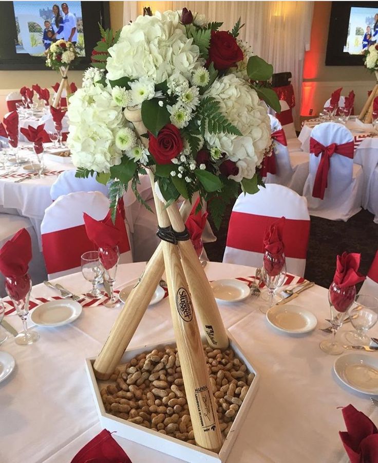 a vase filled with white and red flowers sitting on top of a table covered in place settings