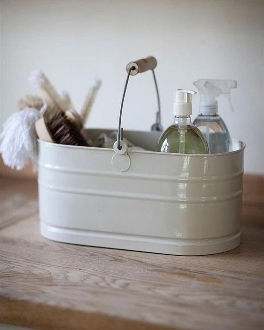 a white container with soap, lotion and other items in it on a wooden table