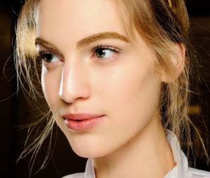 a close up of a woman with blonde hair and blue eyes wearing a white shirt