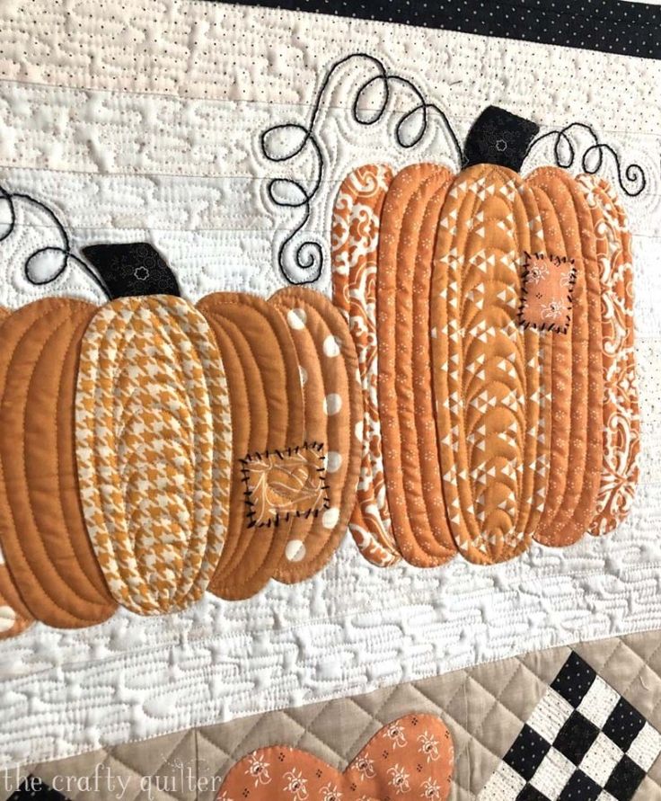 a quilted wall hanging with pumpkins on it