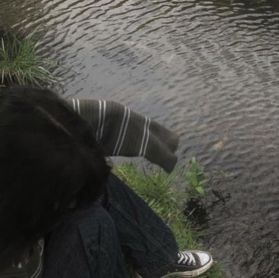 a person sitting on the grass next to a body of water