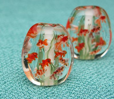 two glass vases sitting on top of a blue cloth covered table next to each other