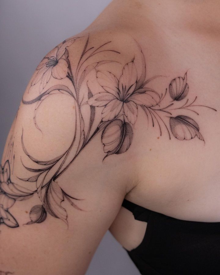 a woman's shoulder with flowers and leaves on the back of her body,