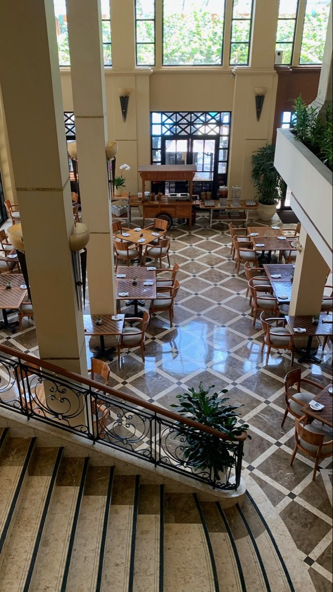 the inside of a restaurant with tables, chairs and planters on the balcony railings