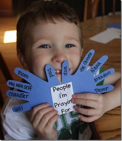 a young boy holding up his handprints with words written on them to spell people i'm praying for