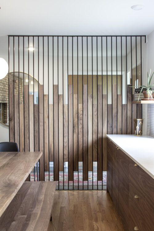 a kitchen with wooden cabinets and white counter tops in front of a wall made of wood slats