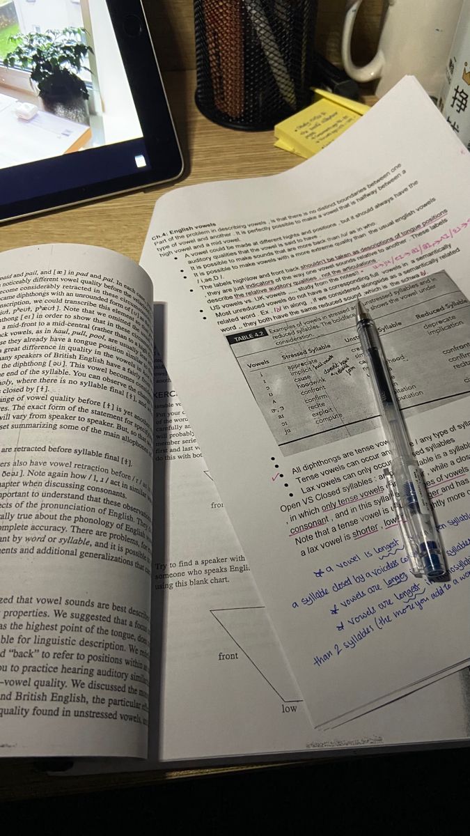 an open book sitting on top of a desk next to a tablet computer and pen