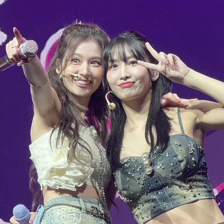 two young women standing next to each other with microphones in their hands and one holding up her hand