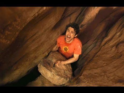 a man is climbing up the side of a rock formation with his mouth open and tongue out