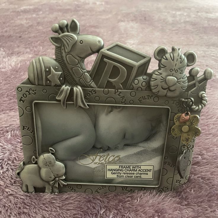 a baby is laying in a photo frame with animals on it's side and the letters r are made out of metal