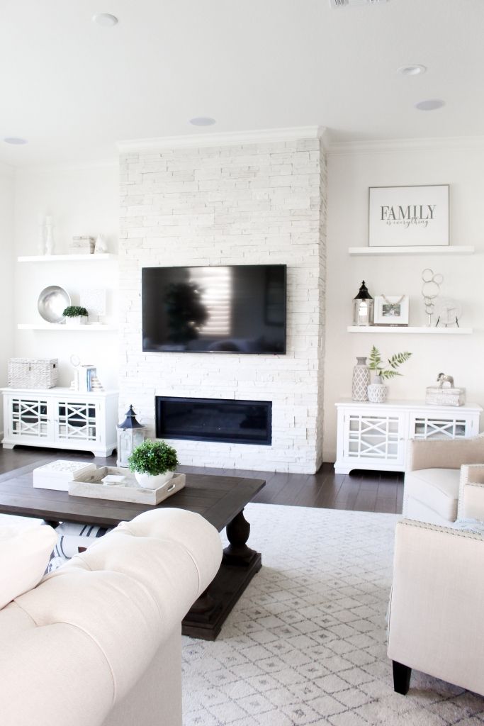 a living room filled with white furniture and a flat screen tv mounted to the wall