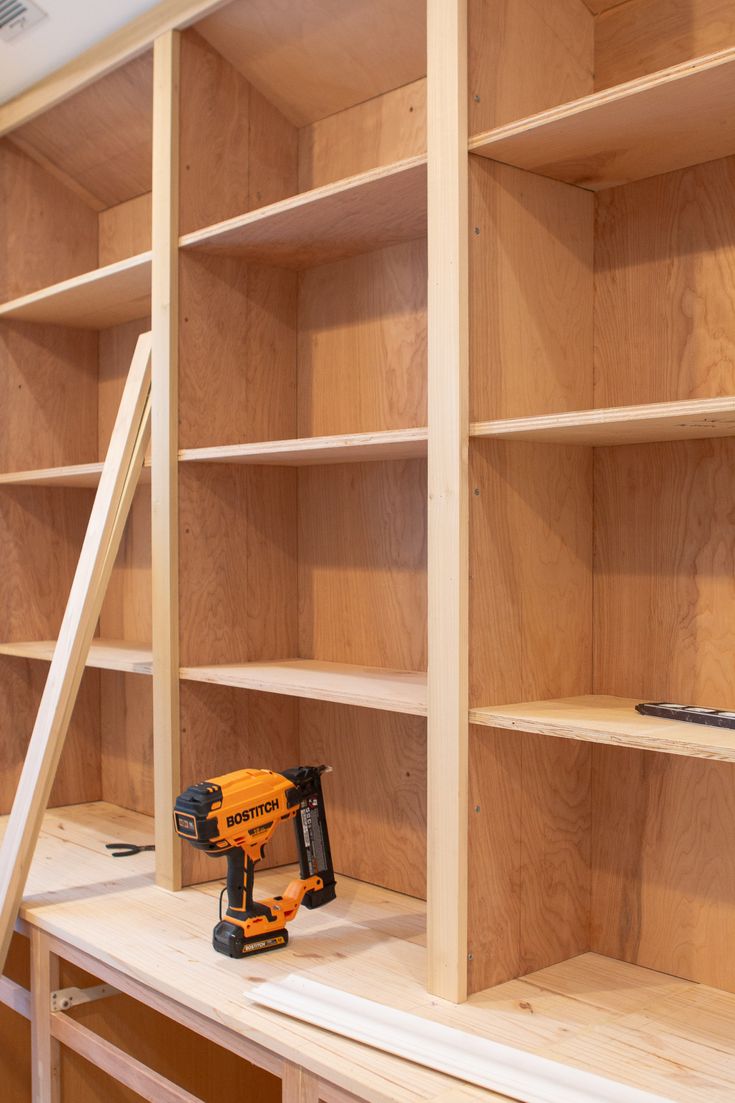 a work bench with tools on it next to some bookshelves and plywood