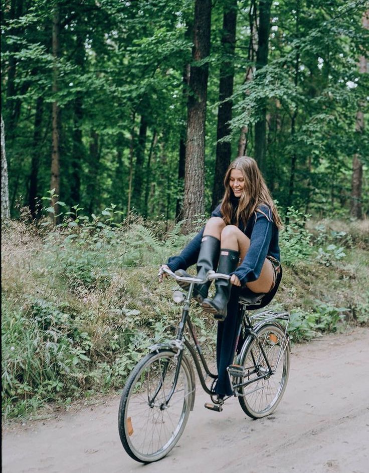 a woman sitting on top of a bike in the middle of a wooded area with trees