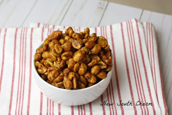 a white bowl filled with nuts sitting on top of a red and white table cloth