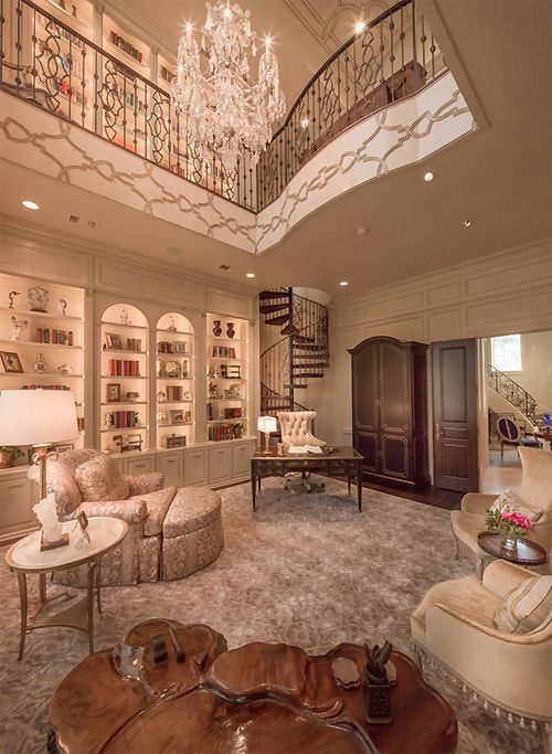 a living room filled with furniture and a chandelier hanging from the top floor