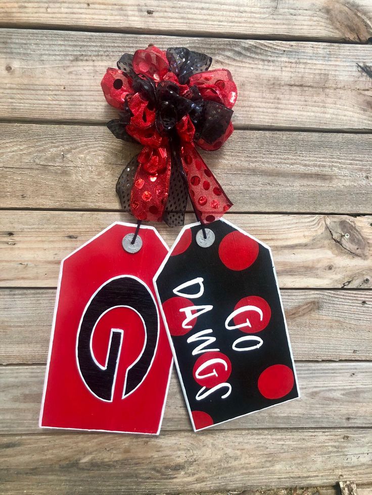 two red and black tags with the word dance on them hanging from a wooden wall