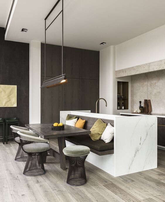 an open kitchen and dining area with marble counter tops, wood flooring, white walls, and gray stools