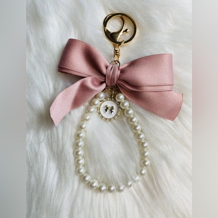 a keychain with a bow and pearls attached to it on a fur surface