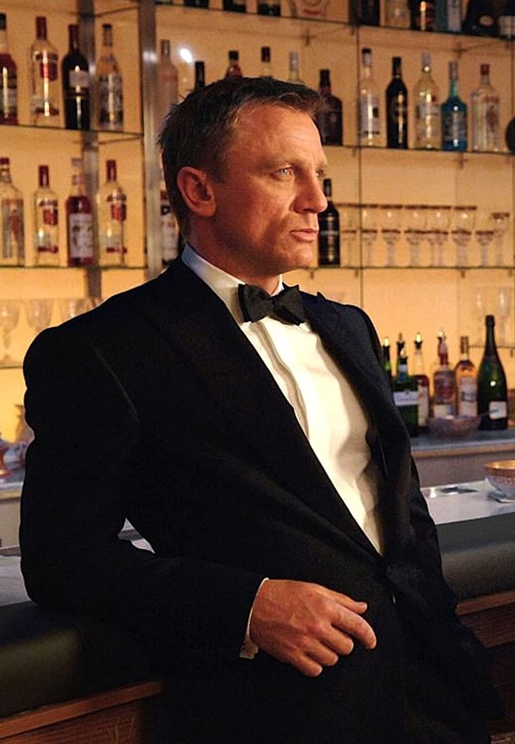 a man in a tuxedo sitting at a bar