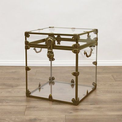 a glass and brass end table with two handles on each side, against a white wall