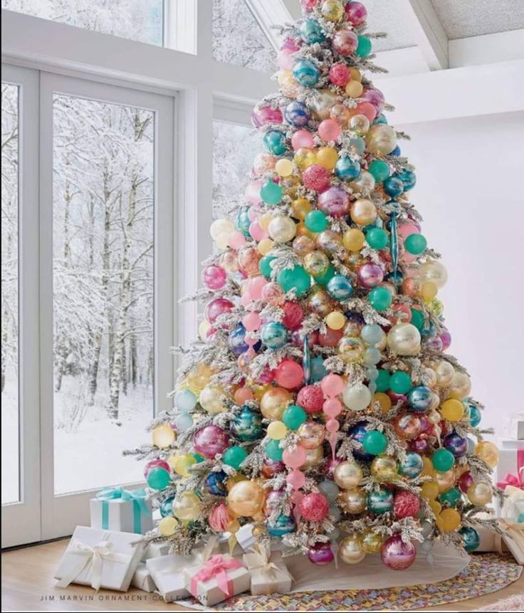 a brightly colored christmas tree in front of a window