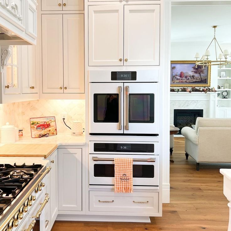 a kitchen with white cabinets and an oven in the center, along with a couch