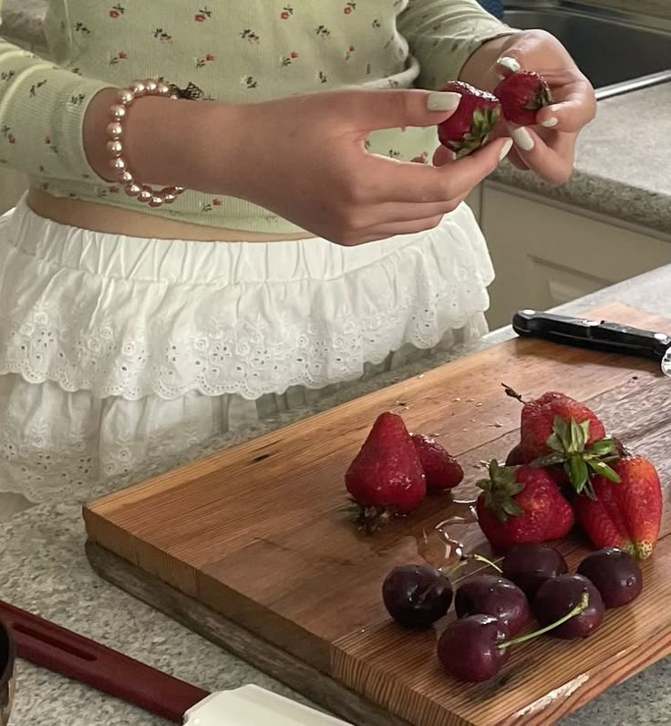 a woman is peeling strawberries on a cutting board