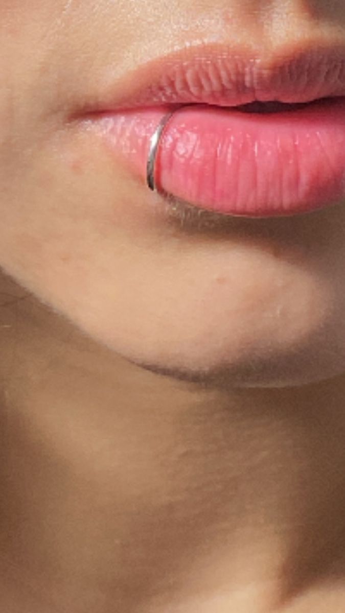 a close up of a woman's lips with a ring on her lip and nose piercing