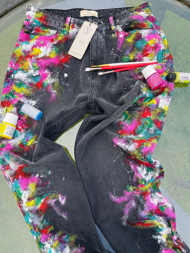 a pair of jeans with paint and pencils on them