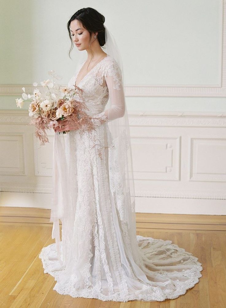 a woman in a wedding dress holding a bouquet and looking down at her left shoulder