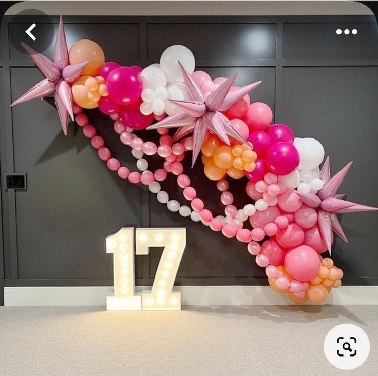 the balloon arch is decorated with pink, orange and white balloons that spell out 17