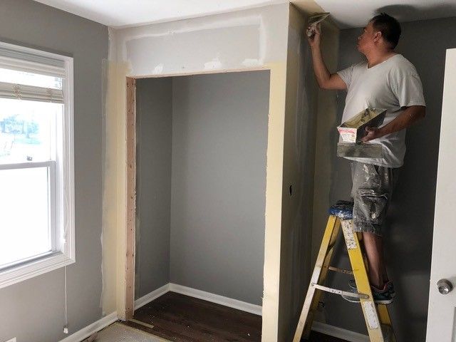 a man standing on a ladder painting the walls in a room that is being remodeled