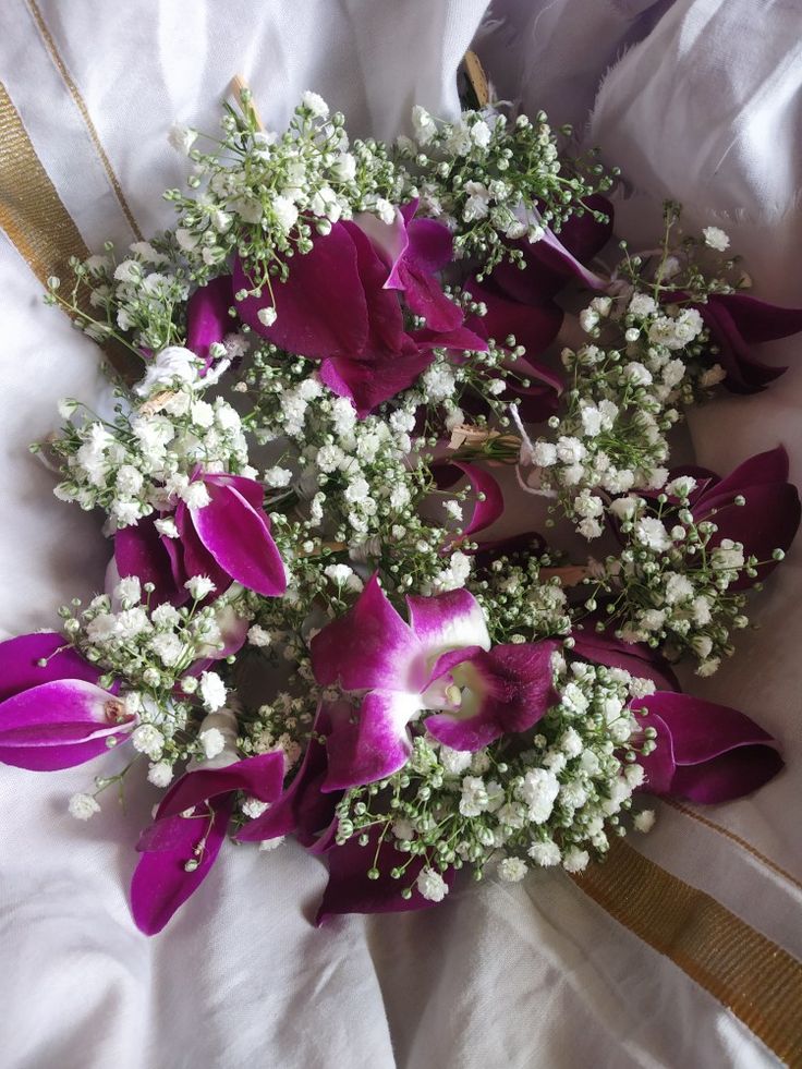 a bouquet of purple and white flowers on a bed