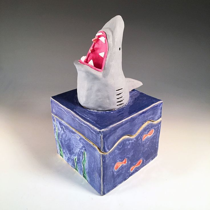 a ceramic shark on top of a box with its mouth open