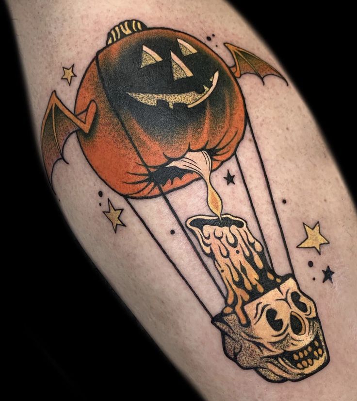 a halloween themed tattoo with a pumpkin flying over a skull on a hot air balloon