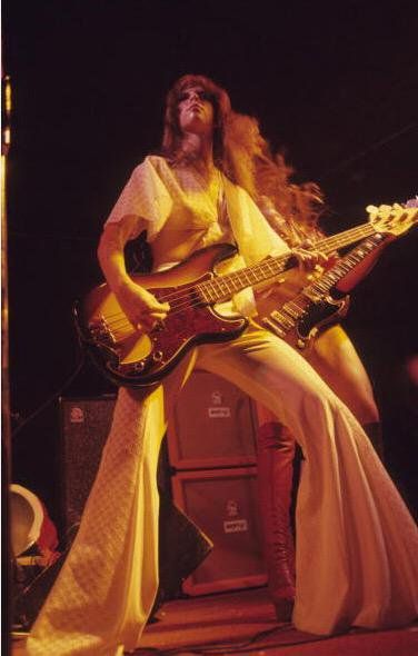 a man with long hair playing guitar on stage