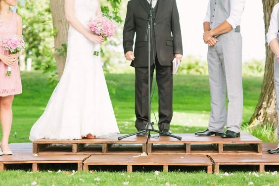 a bride and groom standing at the end of a wooden platform during their wedding ceremony