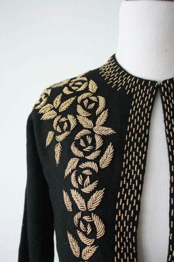 a mannequin wearing a black and gold sweater with an intricate design on it