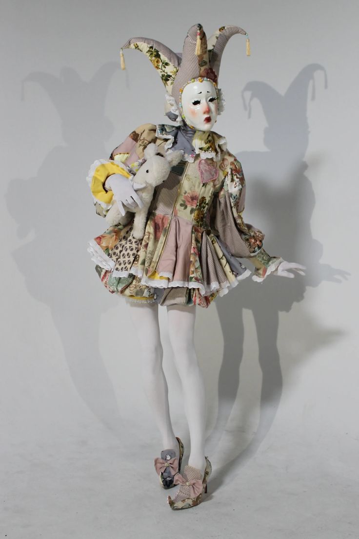 a woman dressed as a clown with stuffed animals on her back and legs, standing in front of a white background